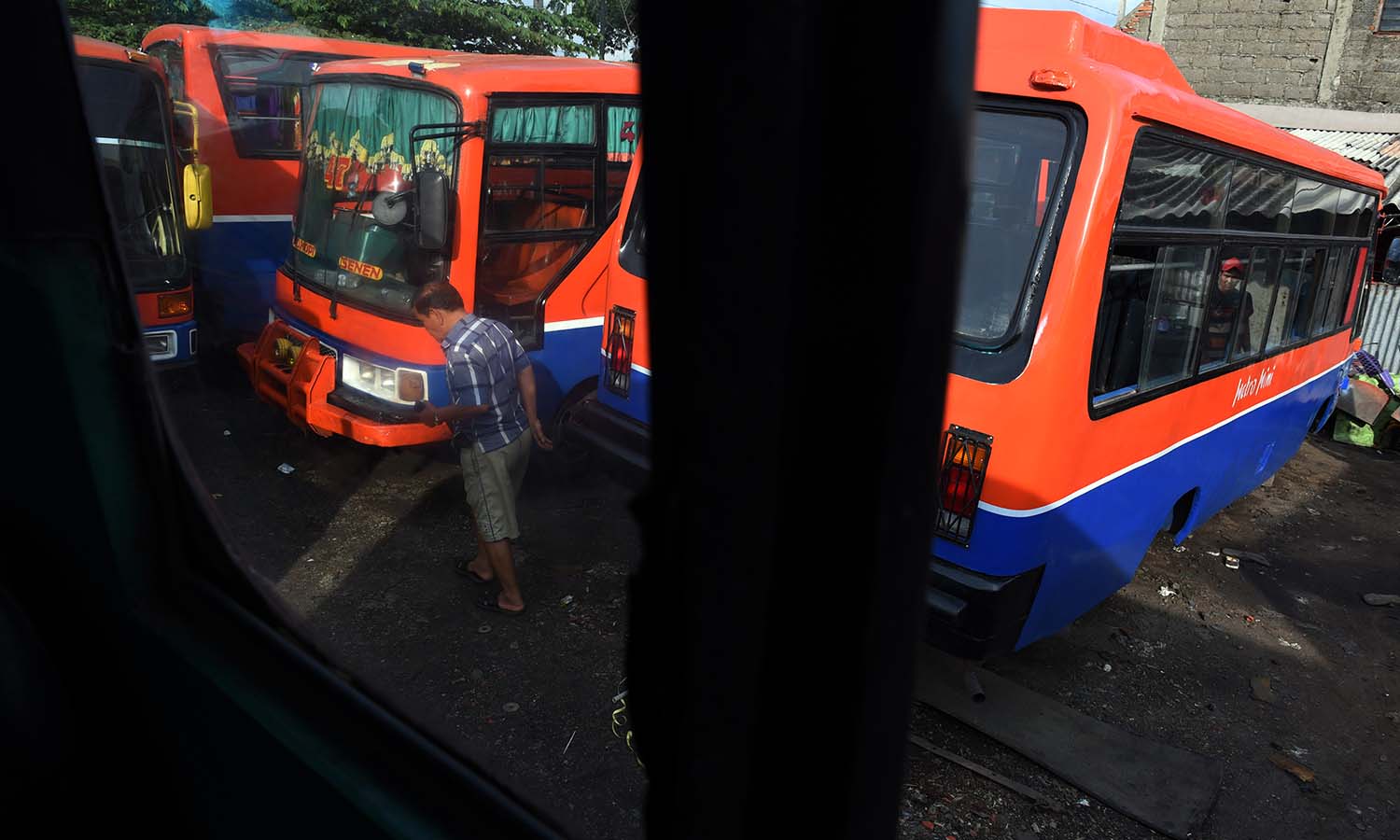 Pemilik Metromini berjalan didekat armadanya ketika tidak beroperasi di Jakarta, Senin (21/12). Sejumlah pemilik angkutan Metromini mengatakan sengaja tidak mengoperasikan armadanya karena takut adanya aksi anarkis dari supir Metromini lainya yang melakukan mogok bila tetap beroperasi. ANTARA FOTO/Hafidz Mubarak A./nz/15
