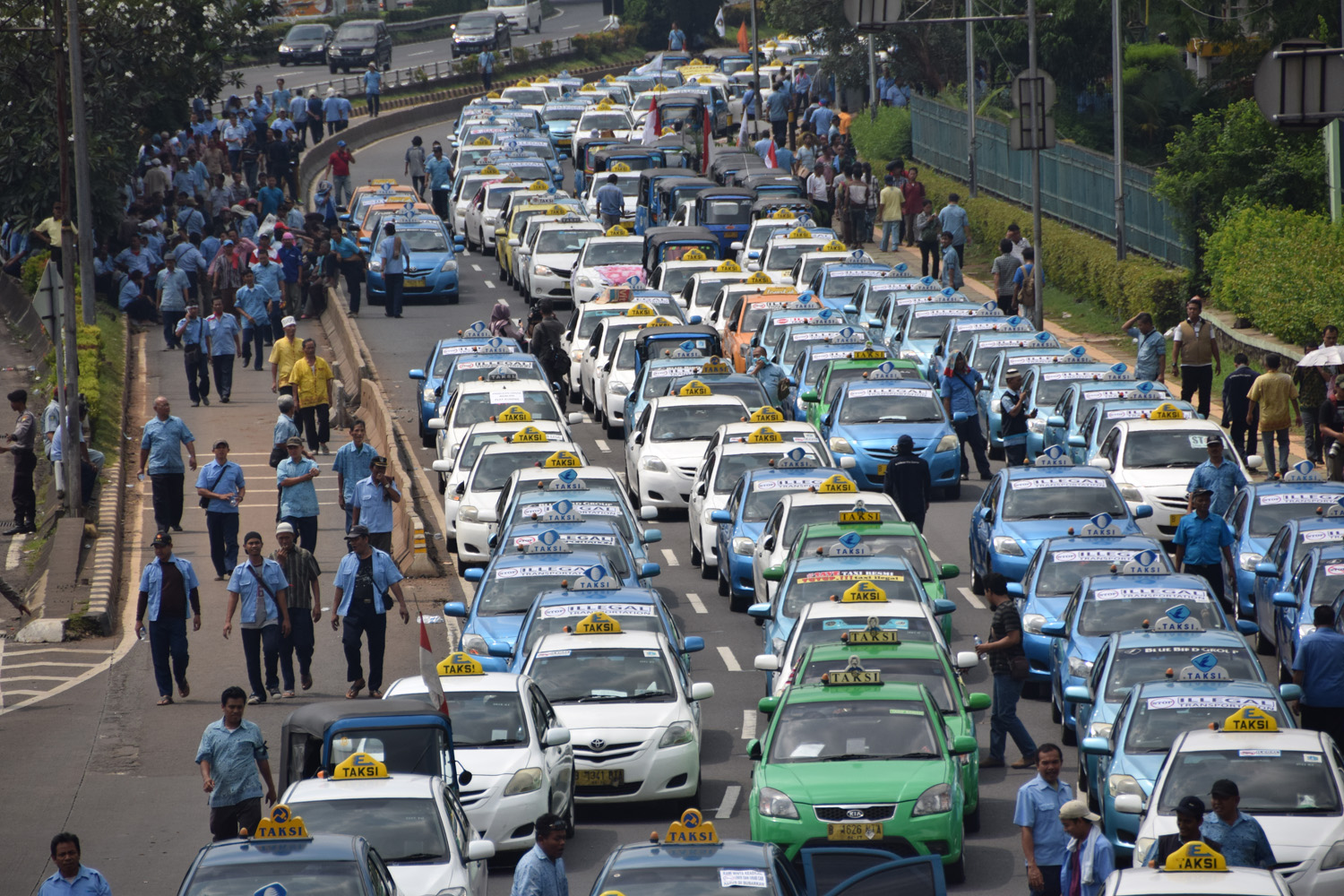 Ratusan angkutan umum jenis taksi terparkir diruas jalan Semanggi saat melakukan unjuk rasa di kawasan Senayan, Jakarta, Selasa (22/3). Dalam aksinya mereka menuntut untuk pemerintah segera menutup armada angkutan plat hitam berbasis aplikasi. TIRTO/Andrey Gromico