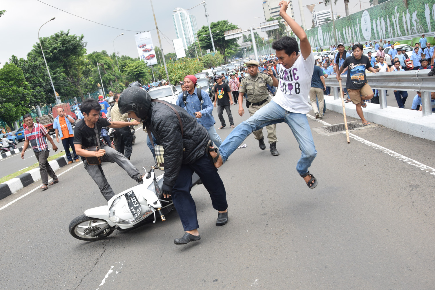 Pendemo menendang pengendara motor ketika Rribuan pengendara angkutan umu berdemontrasi di depan gedung DPR, Selasa, (22/3). TIRTO/Andrey Gromico