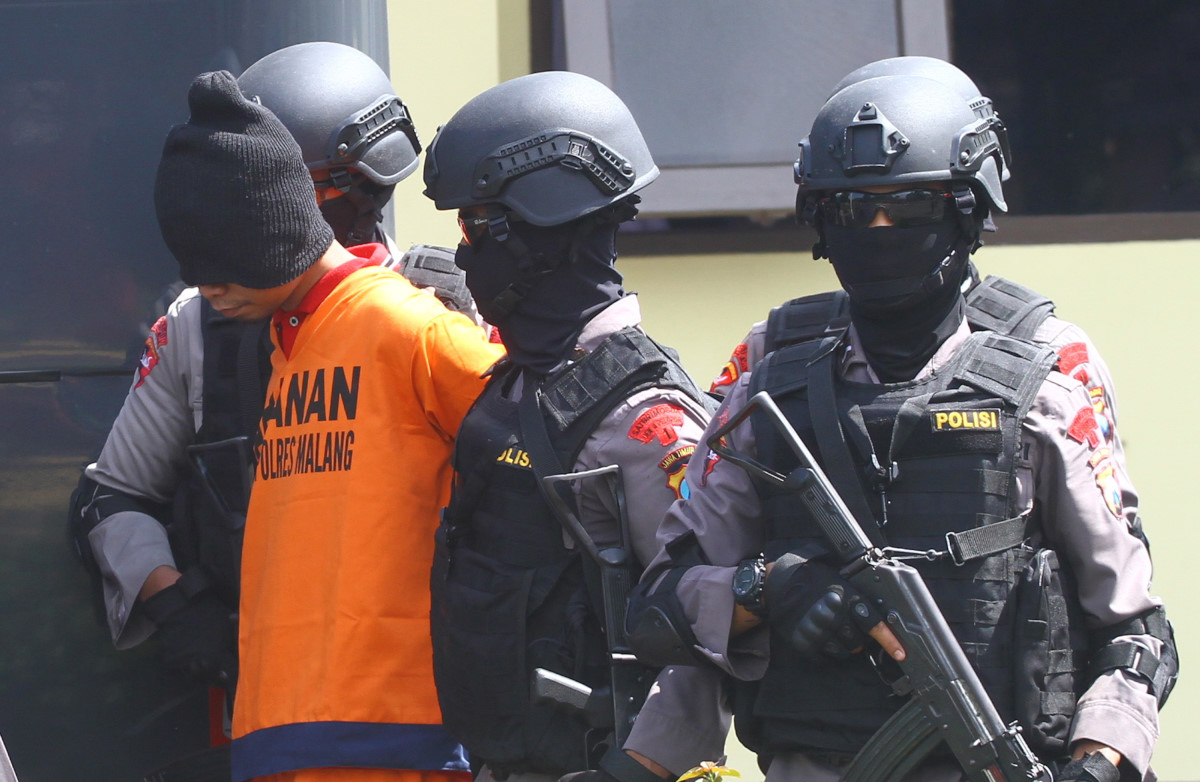 Anggota Brimob bersenjata lengkap menggiring salah satu dari dua tersangka teroris menuju mobil saat dipindahkan di Markas Detasemen B Brimob Ampeldento, Malang, Jawa Timur, Rabu (3/2). Sebelumnya tim Detasemen Khusus (Densus) 88 Anti Teror menangkap dua orang tersebut di sebuah kompleks makam tengah hutan di desa Wagir Malang karena disinyalir terlibat dalam teror bom Thamrin Jakarta. ANTARA FOTO/Ari Bowo Sucipto/aww/16.