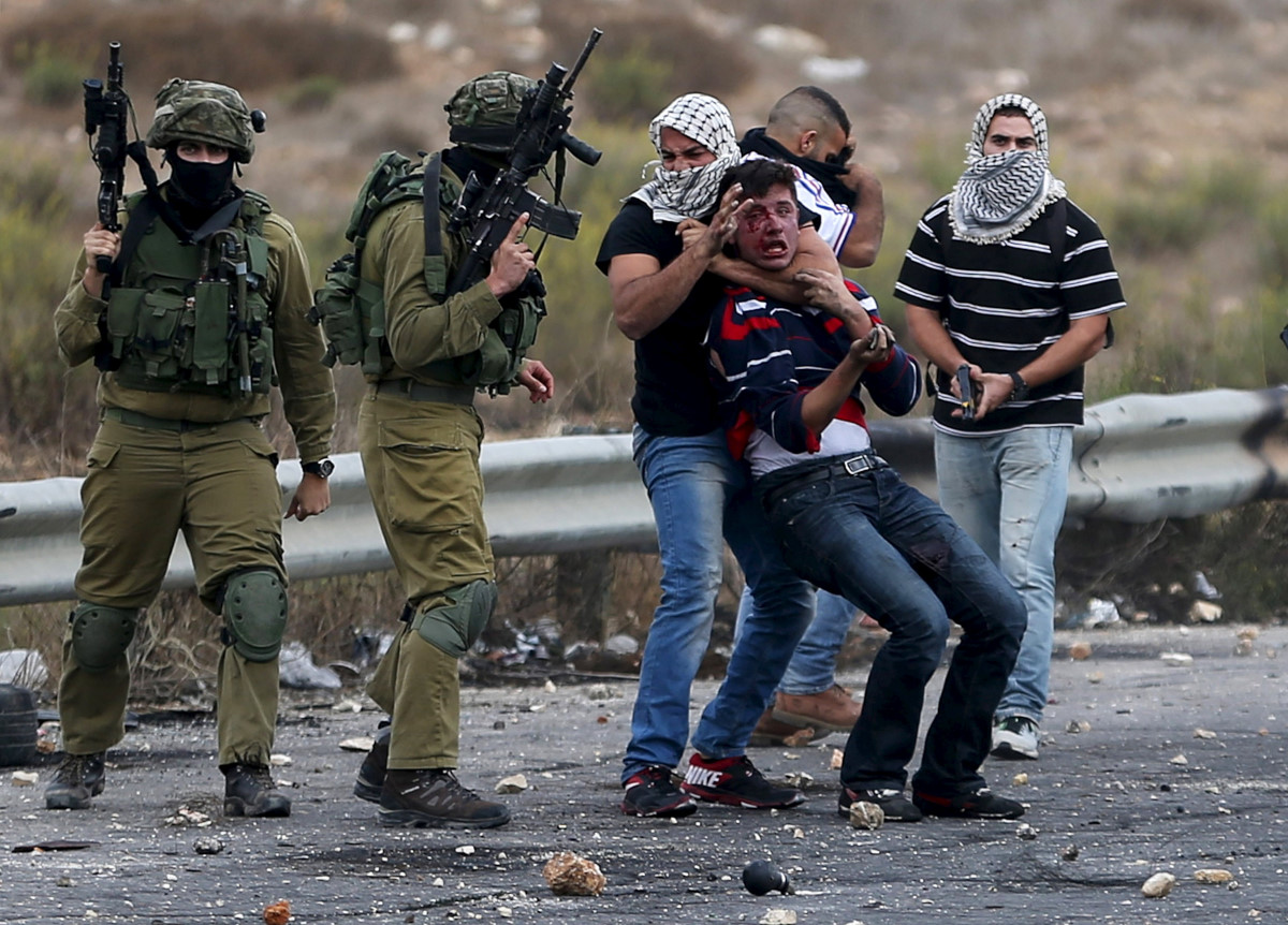 personil Undercover Israel keamanan (R) dan tentara Israel menahan seorang pengunjuk rasa Palestina terluka dalam bentrokan di dekat permukiman Yahudi Bet El, dekat kota Ramallah, Tepi Barat, 7 Oktober 2015. Perdana Menteri Israel Benjamin Netanyahu telah membatalkan perjalanan ke Jerman direncanakan Kamis, sumber pemerintah Jerman mengatakan kepada Reuters, seperti ketegangan meningkat antara Palestina dan Israel setelah sekitar 10 hari kekerasan. GAMBAR REUTERS / Mohamed Torokman
