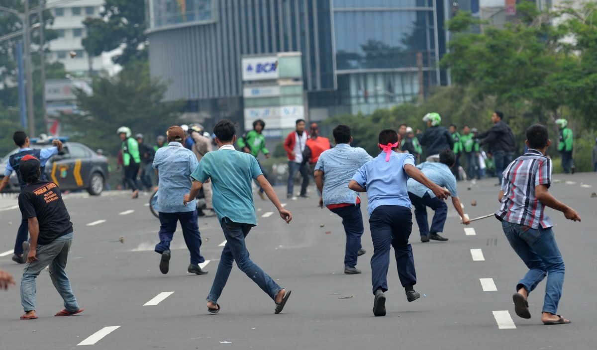 Supir taksi dan pengemudi ojek berbasis aplikasi saling lempar batu saat aksi menolak keberadaan angkutan umum online di Jakarta, Selasa (22/3). Ribuan sopir taksi, bajaj dan sejumlah angkutan umum lainnya melakukan mogok massal untuk menolak keberadaan transportasi umum berbasis aplikasi. ANTARA FOTO/Prasetyo Utomo/foc/16.