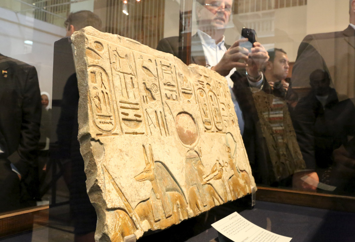 Visitors are seen around an ancient Egyptian artifact 