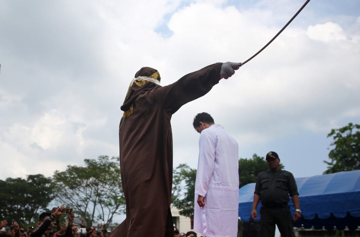 Terpidana pelanggar peraturan daerah (qanun) Syariat Islam (tengah) menjalani hukuman cambuk di halaman Masjid Rukoh, Kecamatan Syiah Kuala, Banda Aceh, Aceh, Selasa (1/3). Mahkamah Syar'iah Kota Banda Aceh menjatuhkan hukuman antara enam hingga 40 kali cambuk terhadap 18 warga yang tertangkap tangan bermain judi (maisir), minuman keras (khamar) dan mesum (khalwat) sesuai qanun Nomor 6/2014 tentang hukum jinayat. ANTARA FOTO/Irwansyah Putra/Spt/16.