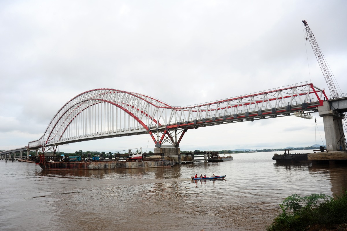 Sebuah perahu motor melintas di bawah Jembatan Tayan yang sedang dibangun, di Desa Tayan, Kecamatan Tayan Hilir, Kabupaten Sanggau, Kalbar, Minggu (2/11). Kepala Dinas Pekerjaan Umum Kalbar, Jakius Sinyor menargetkan pembangunan Jembatan Tayan sepanjang 1.420 meter yang menghubungkan Kalimantan Barat dengan Kalimantan Tengah tersebut, akan rampung pada November 2015. ANTARA FOTO/Jessica Helena Wuysang/pd/15