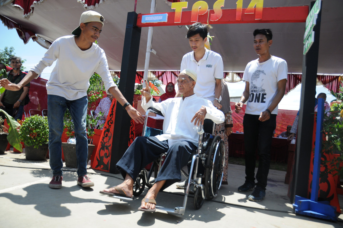 Warga penyandang disabilitas dibantu petugas KPPS usai menggunakan hak pilihnya di TPS Kampung Pilkada RW 03, Depok Jaya, Depok, Jawa Barat, Rabu (9/12). Kampung Pilkada yang berisi 5 TPS dengan 2.200 pemilih itu menyediakan doorpirze dan kendaraan penjemput berupa odong-odong agar warga tertarik menggunakan hak pilihnya. ANTARA FOTO/Indrianto Eko Suwarso/aww/15.