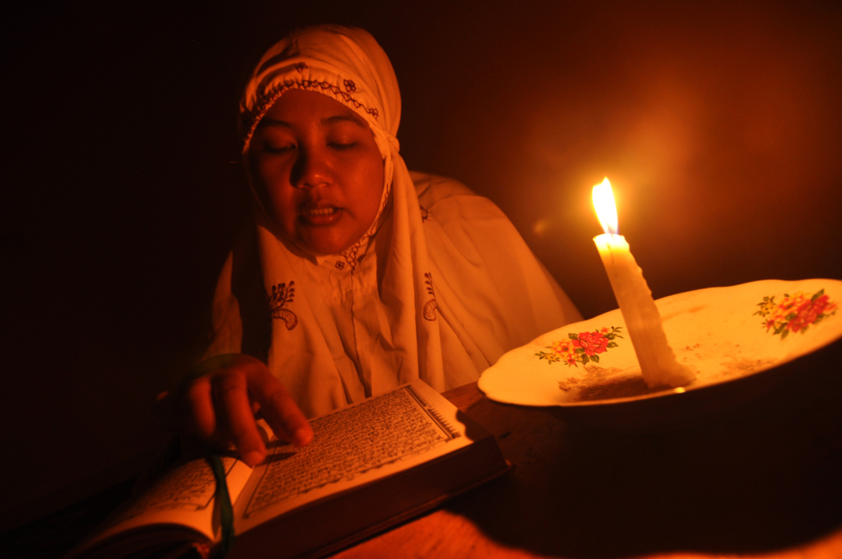 Warga menggunakan penerangan lilin ketika membaca Al Quran saat berlangsungnya pemadaman listrik di Palu, Sulawesi Tengah, Senin (29/2). Beberapa pekan terakhir PLN Area Palu melakukan pemadaman listrik bergilir karena adanya gangguan pada sistem Sulsel yang terkoneksi dengan sistem kelistrikan Palu, Donggala, Parigi dan Sigi (Palapas) hingga mengakibatkan adanya defisit daya. ANTARA FOTO/Mohamad Hamzah/Spt/16.