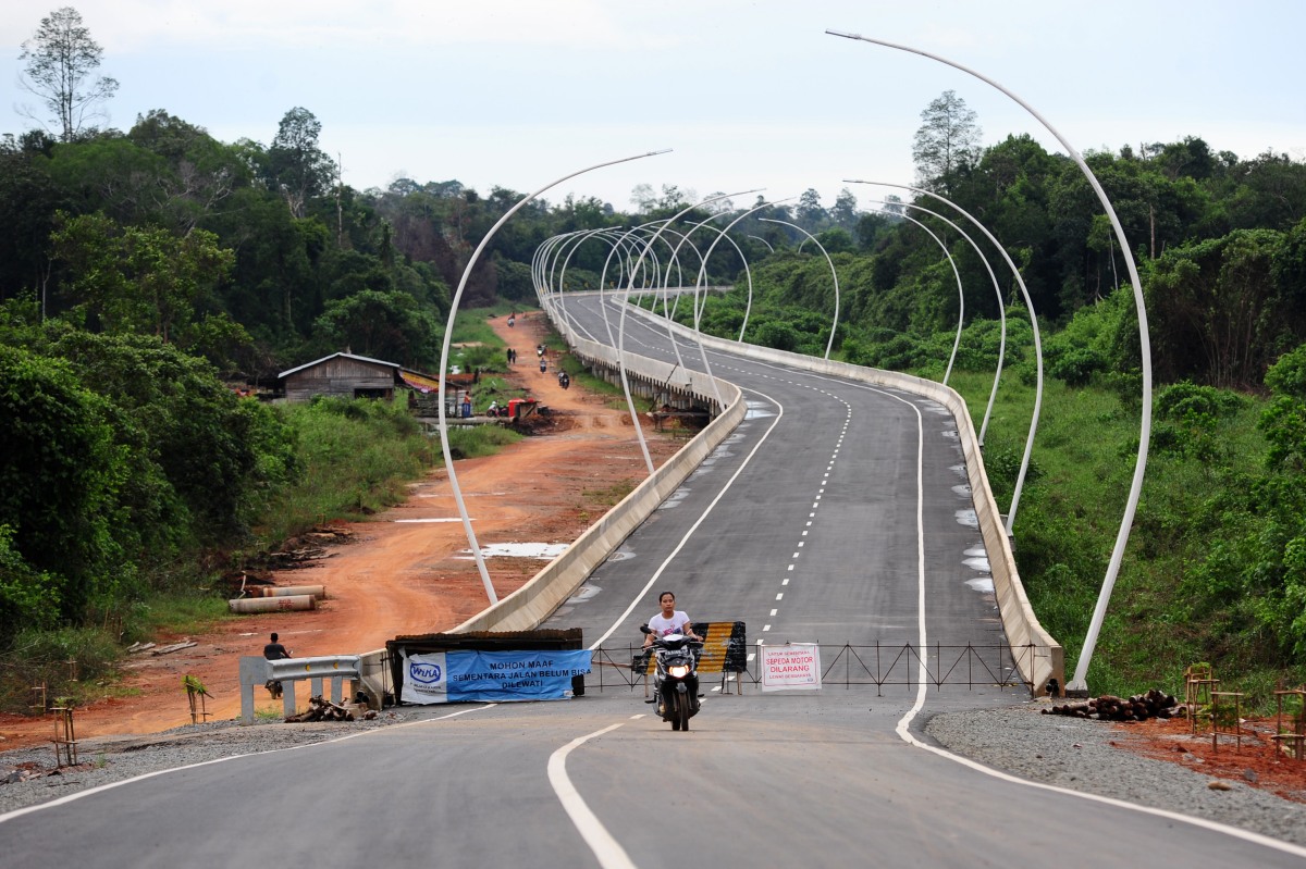 Pengendara motor melintasi Jembatan Tayan yang sedang dibangun, di Desa Tayan, Tayan Hilir, Kabupaten Sanggau, Kalbar, Minggu (2/11). Kepala Dinas Pekerjaan Umum Kalbar, Jakius Sinyor menargetkan pembangunan Jembatan Tayan sepanjang 1.420 meter yang menghubungkan Kalimantan Barat dengan Kalimantan Tengah tersebut, akan rampung pada November 2015. ANTARA FOTO/Jessica Helena Wuysang/pd15