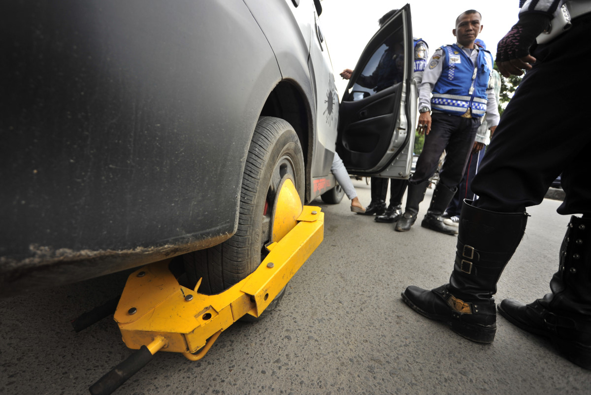 Petugas Dinas Perhubungan Kota Makassar mengunci roda kendaraan yang melakukan parkir liar di Jalan A.P Pettarani Makassar, Sulawesi Selatan, Kamis (5/2). Penertiban parkir liar tersebut dilakukan untuk menghindari kemacetan yang diakibatkan parkir liar yang kerap terjadi di Makassar. ANTARA FOTO/Yusran Uccang/Rei/mes/15.