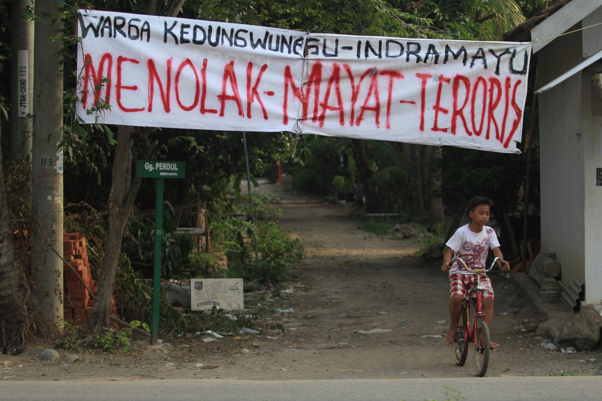 Warga melintas di bawah spanduk penolakan jenasah teroris di desa Kedungwungu, Krangkeng, Indramayu, Jawa Barat, Minggu (17/1). Sebagian warga desa tersebut menolak jenasah teroris Ahmad Muazan untuk dimakamkan di desa mereka. ANTARA FOTO/Dedhez Anggara/16.