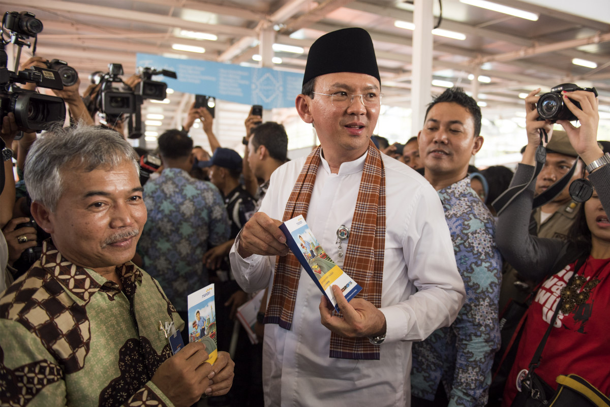 Gubernur DKI Jakarta Basuki Basuki Tjahaja Purnama (tengah) didampingi Regional CEO IV Bank Mandiri Jasmin (kiri) menunjukan brosur E-Money saat peresmian lokasi pedagang kaki lima Lenggang Jakarta di kawasan Monas, Jakarta, Jumat (22/5). Bank Mandiri menyediakan sekitar 339 unit EDC dan 1 unit mobil ATM untuk memudahkan transaksi pedagang dan pengunjung di pusat kuliner dan budaya Lenggang Jakarta. ANTARA FOTO/M Agung Rajasa/ed/mes/15.