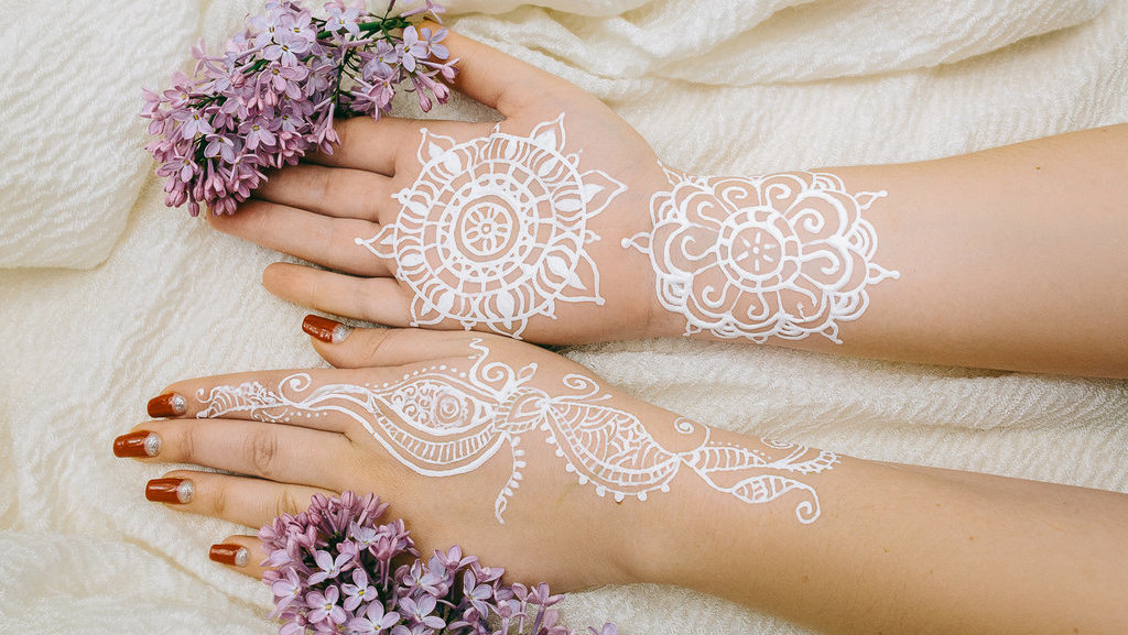 Lukisan bermotif pada tangan perempuan yang dibuat dari tinta putih berbahan Henna. Getty Images/iStockphoto Henna