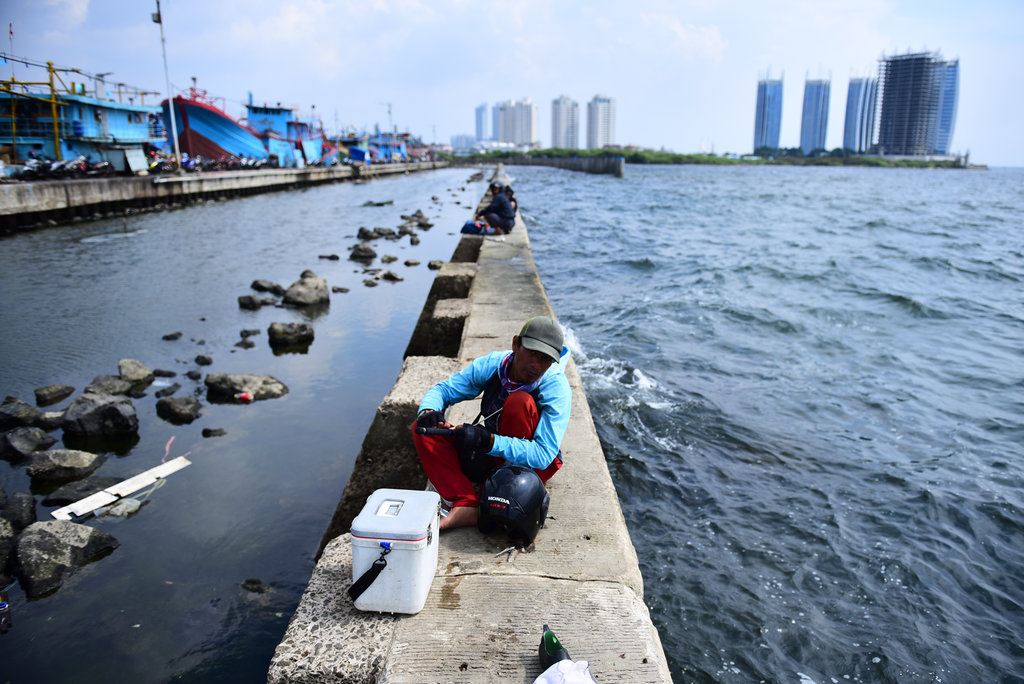 Warga menyiapkan peralatan pancing di atas Tanggul Laut di kawasan Muara Baru, Jakarta, Jumat (22/6/2018). Tanggul Laut di kawasan pesisir Jakarta selain berfungsi melindungi pesisir Jakarta dari Abrasi juga sering dimanfaatkan warga untuk memancing. tirto.id/Arimacs Wilander MEMANCING DI TANGGUL LAUT MUARA BARU