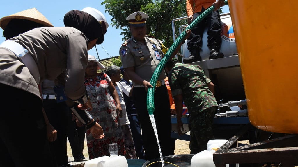 Warga mengantre air bersih saat Bhakti Sosial Polisi Lalu Lintas (Polantas) Polres Magetan bekerja sama dengan Badan Penanggulangan Bencana Daerah (BPBD) setempat di Desa Kuwon, Kecamatan Karas, Kabupaten Magetan, Jawa Timur, Selasa (25/9/2018). ANTARA FOTO/Siswowidodo BANTUAN AIR BERSIH