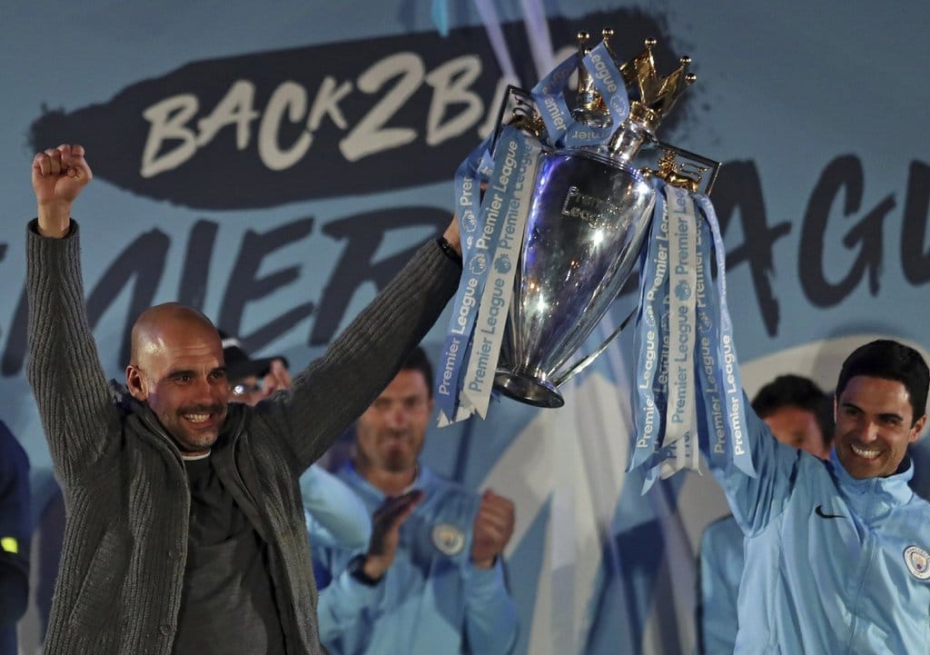 Pelatih Manchester City Pep Guardiola, kiri, dan asistennya Mikel Arteta memegang trofi ketika mereka merayakan dengan pendukung mereka di Stadion Etihad di Manchester, Inggris, Minggu 12 Mei 2019Jon Super/AP Manchester City Menang