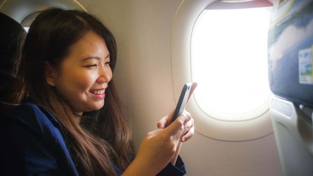 Ilustrasi wanita pakai HP di pesawat. FOTO/iStockphoto Ilustrasi wanita selfie di pesawat