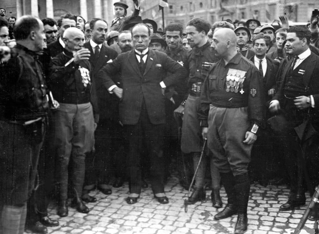 Pemimpin Fasis Italia Benito Mussolini, tengah, bertumpu pada pinggul, dengan anggota Partai fasis, di Roma, Italia, 28 Oktober 1922, setelah bulan Maret di Roma. Setelah pawai, Raja Emanuelle III meminta Mussolini untuk membentuk pemerintahan baru. FOTO/AP Benito Mussolini