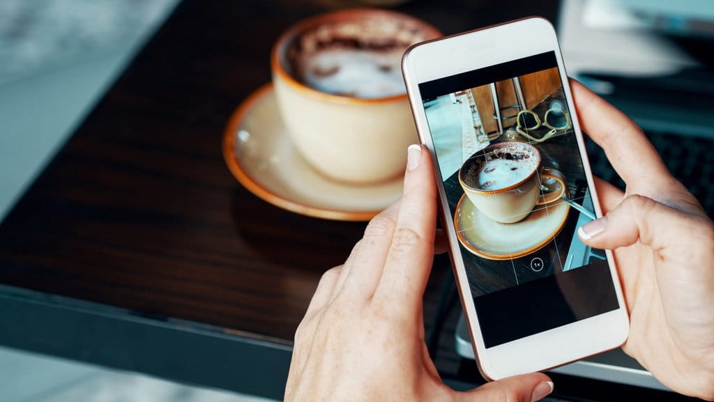 Seseorang mengambil foto kopi menggunakan Smartphone. FOTO/iStockphoto Ilustrasi FOTO