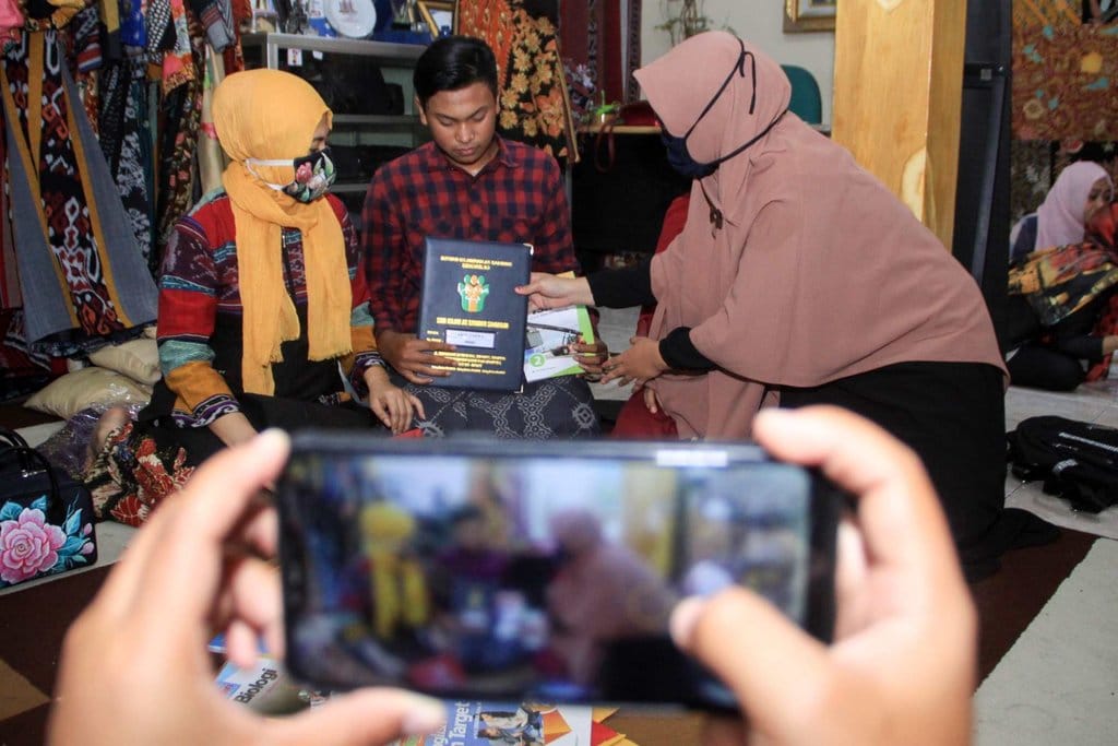 Seorang guru menyerahkan rapor dan perlengkapan sekolah di rumah wali murid di kawasan Gelam, Candi, Sidoarjo, Jawa Timur, Selasa (23/6/2020). ANTARA FOTO/Umarul Faruq/foc. GURU BAGIKAN RAPOR KE RUMAH ANAK DIDIK