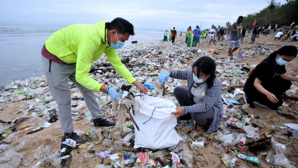 Relawan membersihkan sampah yang berserakan saat mengikuti aksi bersih sampah di Pantai Kuta, Badung, Bali, Rabu (6/1/2021). ANTARA FOTO/Fikri Yusuf/aww. AKSI BERSIH SAMPAH PANTAI KUTA