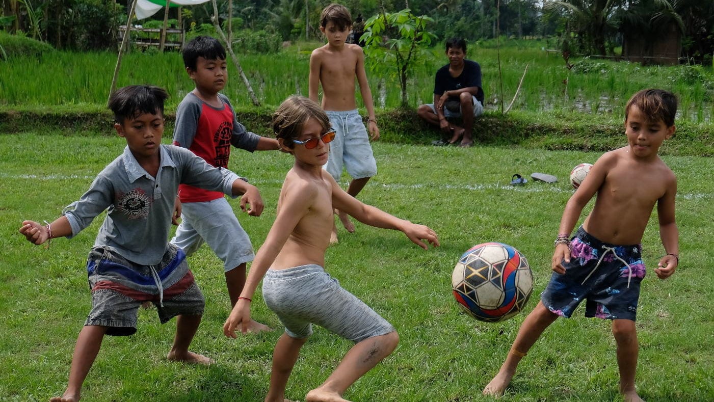 Anak ekspatriat bersama anak-anak desa setempat bermain sepak bola saat memperingati Hari Anak Sedunia di Sekolah Alam Empathy Center, Desa Pejeng Kangin, Gianyar, Bali, Jumat (19/11/2021). ANTARA FOTO/Nyoman Hendra Wibowo/foc. MEMPERINGATI HARI ANAK SEDUNIA DI BALI