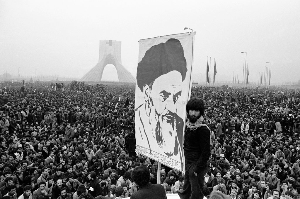 Para demonstran mengangkat poster pemimpin Muslim Ayatollah Ruhollah Khomeini yang diasingkan selama demonstrasi anti-Syah di Teheran, Iran. Monumen. Revolusi Islam Iran mengubah sekutu kuat AS menjadi musuh regional. Peristiwa klimaks ini dan lainnya pada tahun 1979, yang mendominasi televisi dan halaman depan surat kabar 40 tahun yang lalu, membantu membentuk Timur Tengah modern. (Foto AP/Michel Lipchitz, File) Ayatollah Khomeini