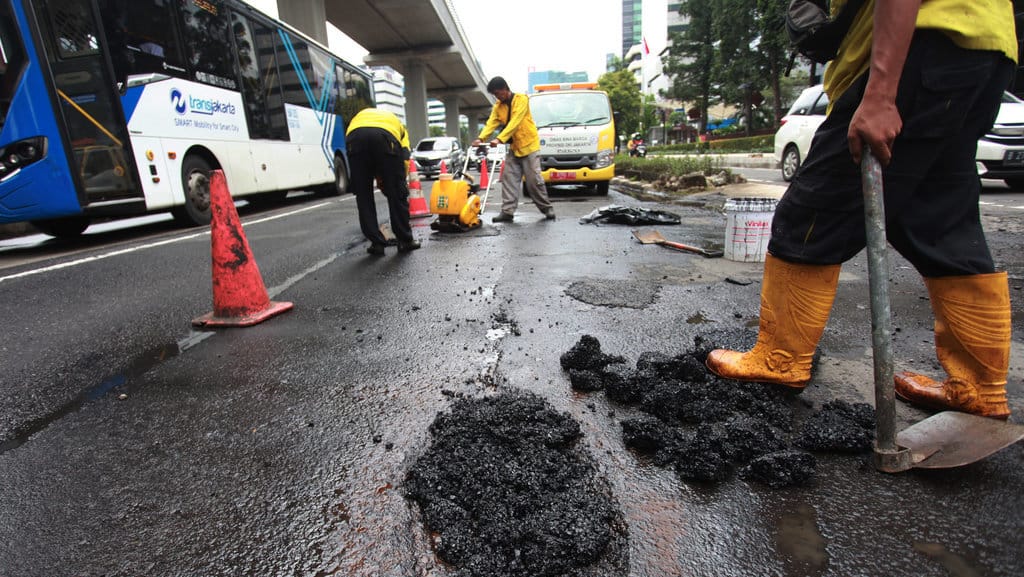 Sejumlah pekerja memperbaiki jalan yang rusak di Jalan HR Rasuna Said, Jakarta, Kamis (5/1/2023). ANTARA FOTO/Reno Esnir/YU PERBAIKAN JALAN RUSAK