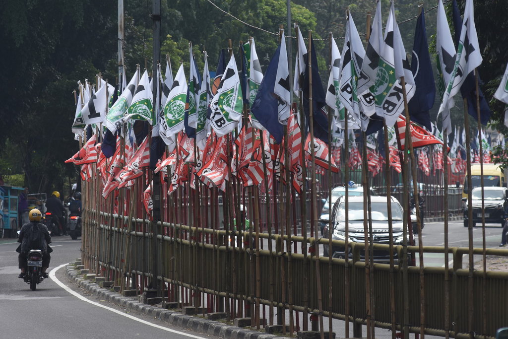 Pengendara melintas di dekat bendera parpol yang terpasang di pembatas jalan kawasan Tebet, Jakarta, Senin (17/7/2023). ANTARA FOTO/Indrianto Eko Suwarso/rwa. Bendera parpol bertebaran