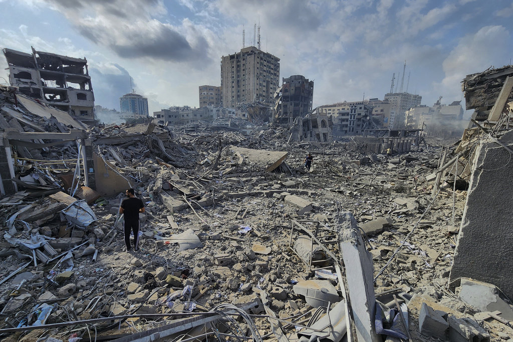 Warga Palestina berjalan melewati puing-puing bangunan yang hancur akibat serangan udara Israel di Kota Gaza pada Selasa, 10 Oktober 2023. (AP Photo/Hassan Eslaiah) Perang Israel dan Hamas Palestina
