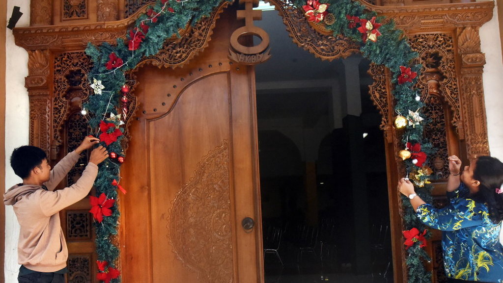 Panitia perayaan Natal memasang bunga dan lampu hias di pintu masuk gereja HKBP Kota Serang di Serang, Banten, Rabu (20/12/2023). ANTARA FOTO/Asep Fathulrahman/Spt. Persiapan Misa Natal di Banten