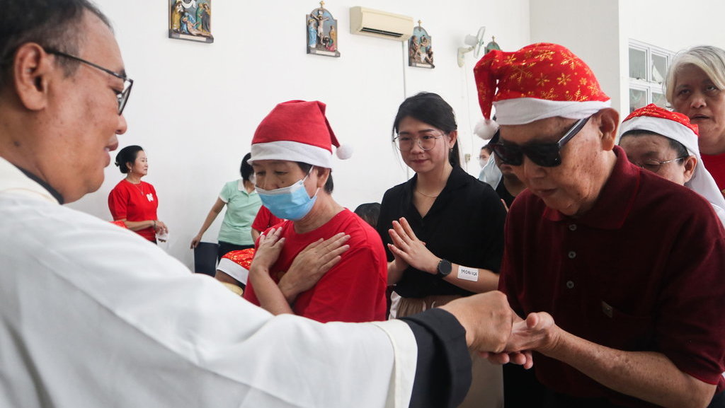 Romo memberikan hosti atau roti jamuan kepada seorang lansia dalam Misa Hari Raya Natal 2023 di Panti Lansia Santa Anna, Jakarta, Senin (25/12/2023). ANTARA FOTO/ Putri Hanifa/wpa/nym. Misa Natal di Panti Lansia Santa Anna