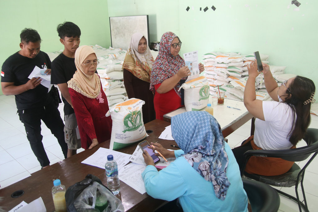 Petugas mendokumentasikan warga penerima manfaat saat pengambilan bantuan pangan cadangan beras di Balai Kelurahan Bangsal, Kediri, Jawa Timur, Rabu (14/8/2024). ANTARA FOTO/Prasetia Fauzani/nym. Penyaluran bantuan pangan di Kota Kediri