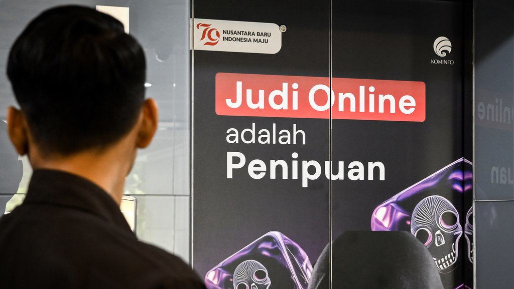 Seorang pria berdiri di depan poster sosialisasi tentang judi online di Gedung Kementerian Komunikasi dan Informatika, Jakarta, Rabu (11/9/2024). ANTARA FOTO/Sulthony Hasanuddin/nym. Upaya Kominfo mengatasi judi online