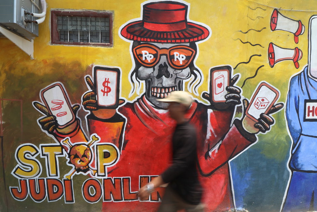 Warga melintas di depan mural bertema cegah judi online di Kediri, Jawa Timur, Rabu (9/10/2024). ANTARA FOTO/Prasetia Fauzani/foc. Mural cegah judi online oleh polisi