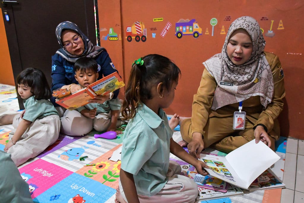 Dua petugas membacakan buku kepada anak yang diasuh di Taman Anak Sejahtera Arutala (TAS), Kebon Bawang, Jakarta Utara, Senin (5/5/2025). ANTARA FOTO/Sulthony Hasanuddin/bar Tempat penitipan anak gratis di Jakarta