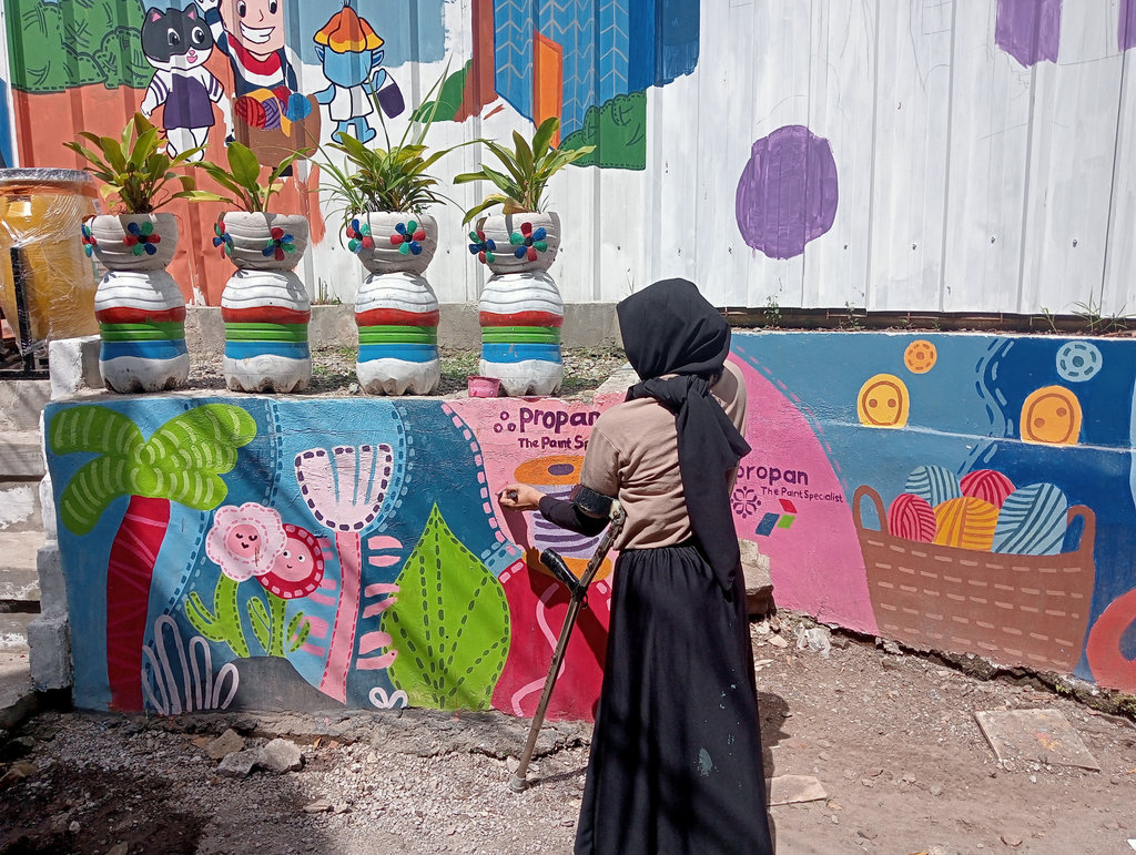 Kawan-kawan Difabel dari Merajut Asa mewarnai mural di Gang Masjid Binong Jati, Kota Bandung. Sabtu (12/6/2025). Tirto.id/Firman Kampung Rajut Binong Jati