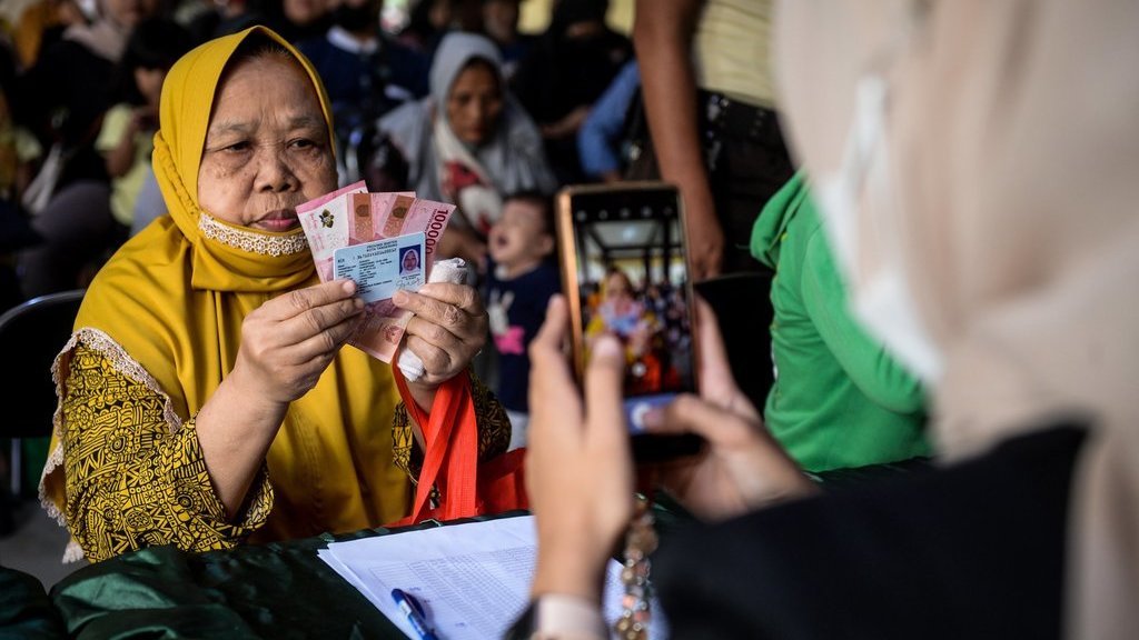 Petugas memotret warga memperlihatkan uang tunai saat penyaluran bantuan sosial di Kota Tangerang, Banten, Selasa (12/8/2025). ANTARA FOTO/Putra M. Akbar/foc. Realisasi penyaluran bantuan sosial di Banten