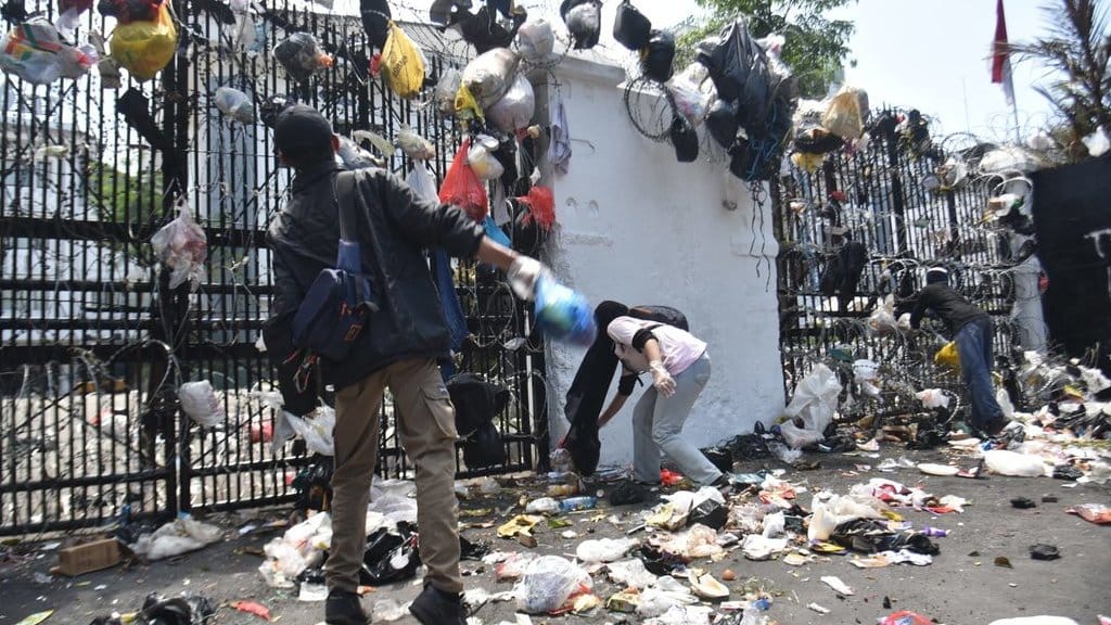 Puluhan warga yang tergabung dalam Forum Warga Kampung Kota melemparkan sampah ke halaman Gedung DPRD Jabar, Kota Bandung, pada Kamis (4/9/2025) siang. Sejumlah sampah yang dibungkus kantong kresek itupun tampak tersangkut di pintu gerbang gedung. tirto.id/Amad NZ. Sampah tersangkut di Gedung DPRD Jabar