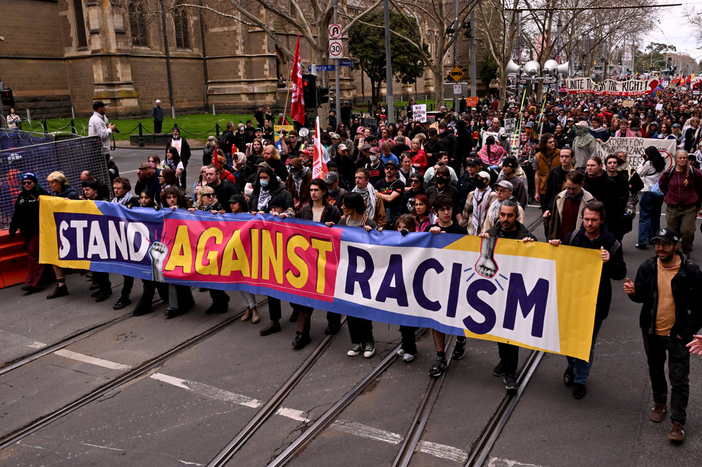 Orang-orang mengangkat spanduk dan plakat selama pawai protes anti-rasisme di Melbourne pada 13 September 2025 untuk melawan pengunjuk rasa anti-imigrasi dan anti-pemerintah dari demonstrasi Save Australia. (Photo by William WEST / AFP) Demo di Australia