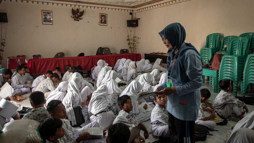 Seorang guru SDN 1 Sayung mengajar muridnya di Kantor Balai Desa Sayung, Kecamatan Sayung, Demak, Jawa Tengah, Rabu (5/11/2025). ANTARA FOTO/Aji Styawan/tom. Kegiatan belajar mengajar terdampak banjir di Demak