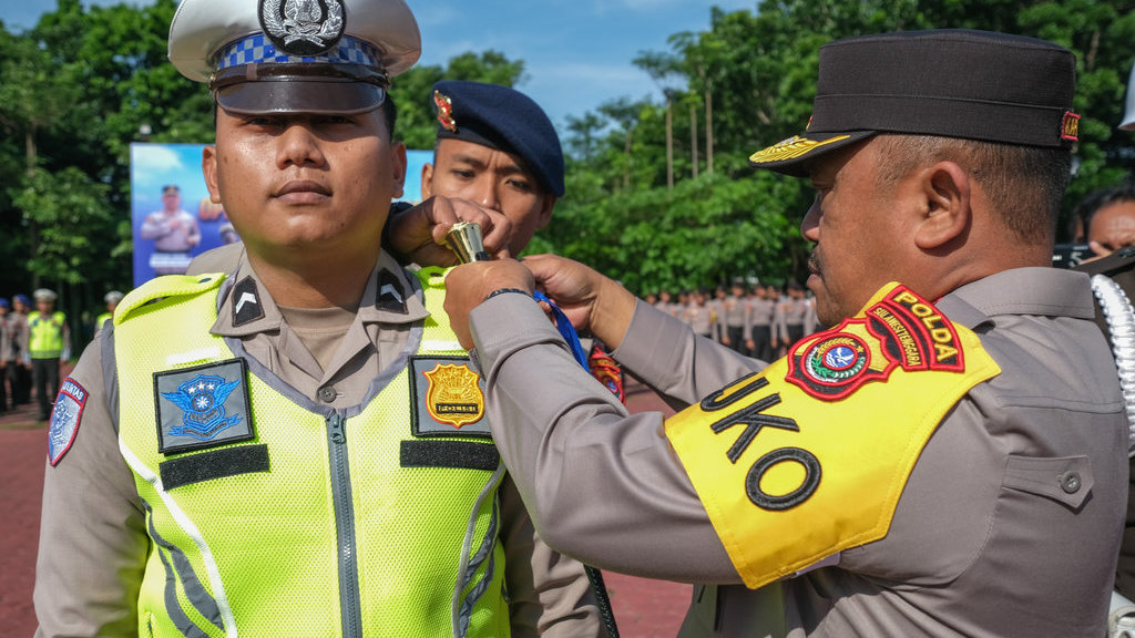 Kapolda Sultra Irjen Pol Didik Agung Widjanarko (kanan) menyematkan pita operasi kepada personel kepolisian yang akan bertugas pada Apel Gelar Pasukan Operasi Zebra Anoa 2025 di Lapangan Mako Polda Sultra, Senin (17/11/2025). ANTARA FOTO/Andry Denisah/foc. Gelar pasukan Operasi Zebra Anoa 2025
