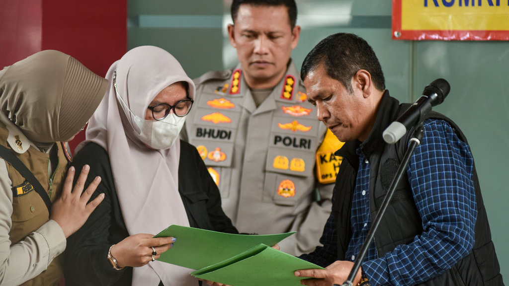 Personel Polri (kanan) memberikan dokumen jenazah kepada keluarga korban kebakaran perusahaan nirawak di Rumah Sakit Polri, Jakarta Timur, Rabu (10/12/2025). ANTARA FOTO/Fakhri Hermansyah/YU Polisi mengidentifikasi 10 korban kebakaran perusahaan nirawak