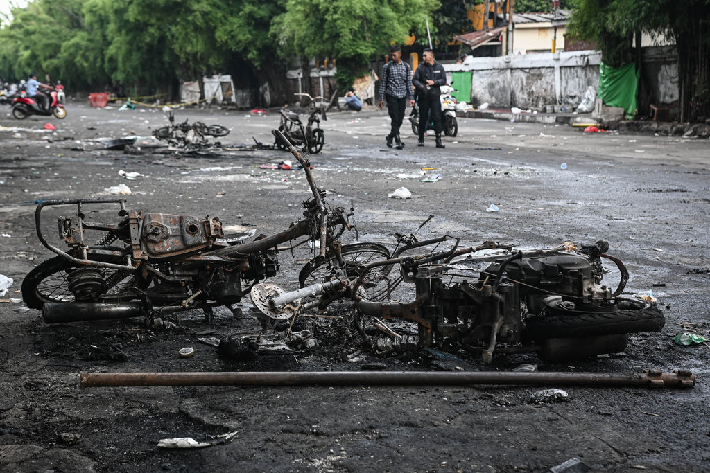 Warga melintas di samping sepeda motor yang terbakar pascakericuhan di kawasan Kalibata, Jakarta, Jumat (12/12/2025). ANTARA FOTO/Sulthony Hasanuddin/nym. Kondisi pascakericuhan di Kalibata