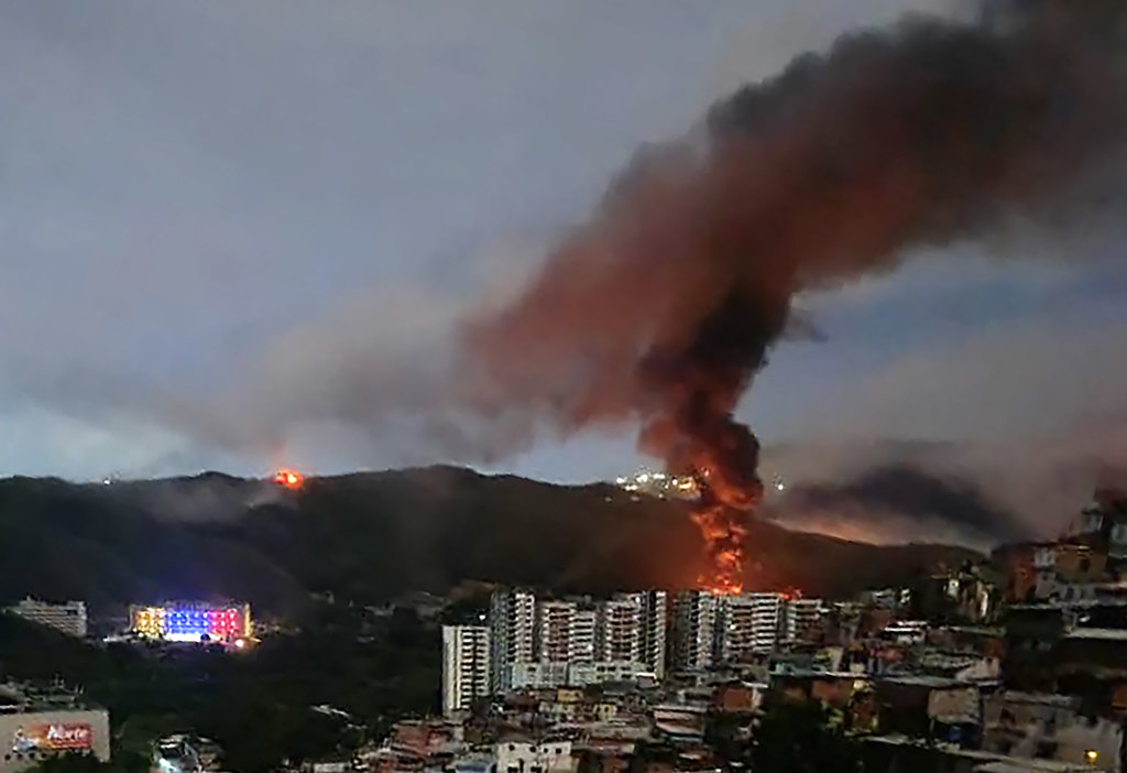 Kebakaran di Fuerte Tiuna, kompleks militer terbesar Venezuela, terlihat dari kejauhan setelah serangkaian ledakan di Caracas pada 3 Januari 2026. Foto/AFP Serangan di Venezuela