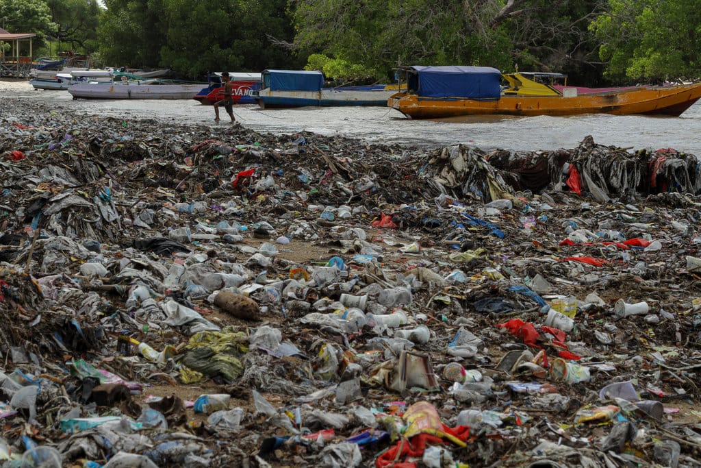 Seorang warga menarik tali perahu melewati tumpukkan sampah di Pesisir Taman Wisata Laut Teluk Kupang, Kota Kupang, Nusa Tenggara Timur, Kamis (29/1/2026). Sampah kiriman berupa plastik tersebut memenuhi pesisir akibat terbawa aliran air hujan dari permukiman sekitar yang bermuara ke laut, kondisi tersebut mencemari kawasan wisata laut dan mengancam ekosistem pesisir. ANTARA FOTO/Mega Tokan/bar Taman Wisata Laut Teluk Kupang dipenuhi sampah