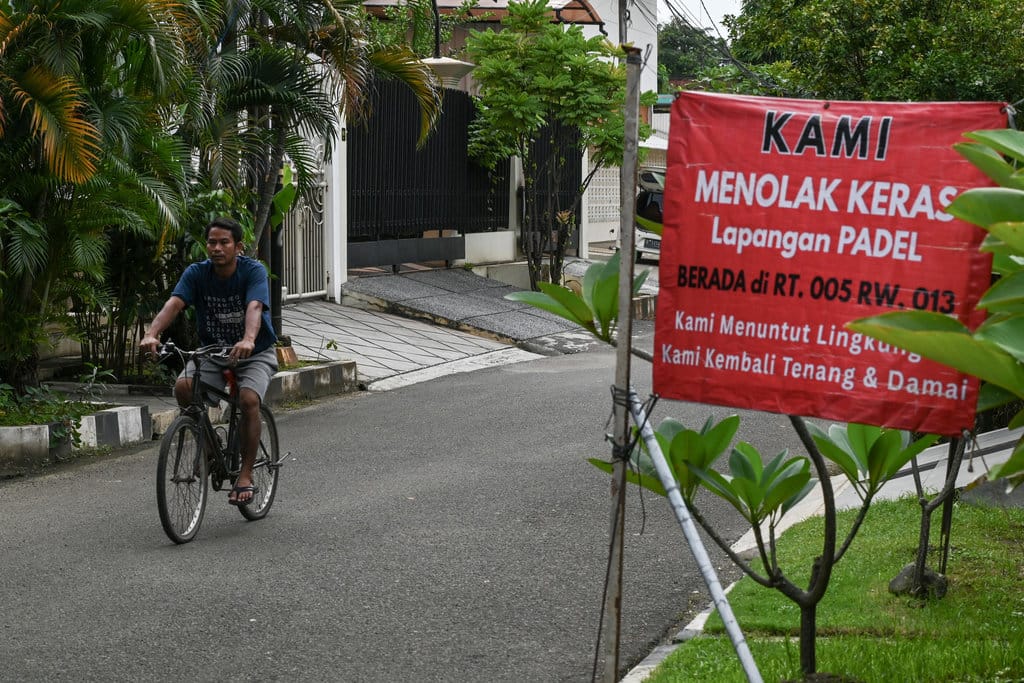 Pesepeda melintas di samping banner penolakan lapangan padel di Pulomas, Jakarta, Selasa (24/2/2026). Menurut warga aksi penolakan menggunakan banner karena tidak pernah dimintai persetujuan pembangunan lapangan dari pihak pengelola dan Pemkot Jakarta Timur akan membahas terkait izin bangunan bersama organisasi perangkat daerah (OPD). ANTARA FOTO/Fakhri Hermansyah/nz Aksi penolakan lapangan padel di permukiman Pulomas