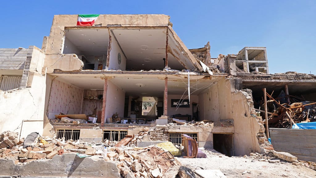 Bendera Iran terlihat di atas sebuah bangunan tempat tinggal yang rusak akibat serangan baru-baru ini di kota Vahdat di Karaj, barat daya Teheran pada 3 April 2026. (Foto oleh ATTA KENARE / AFP) Rumah rusak di Iran