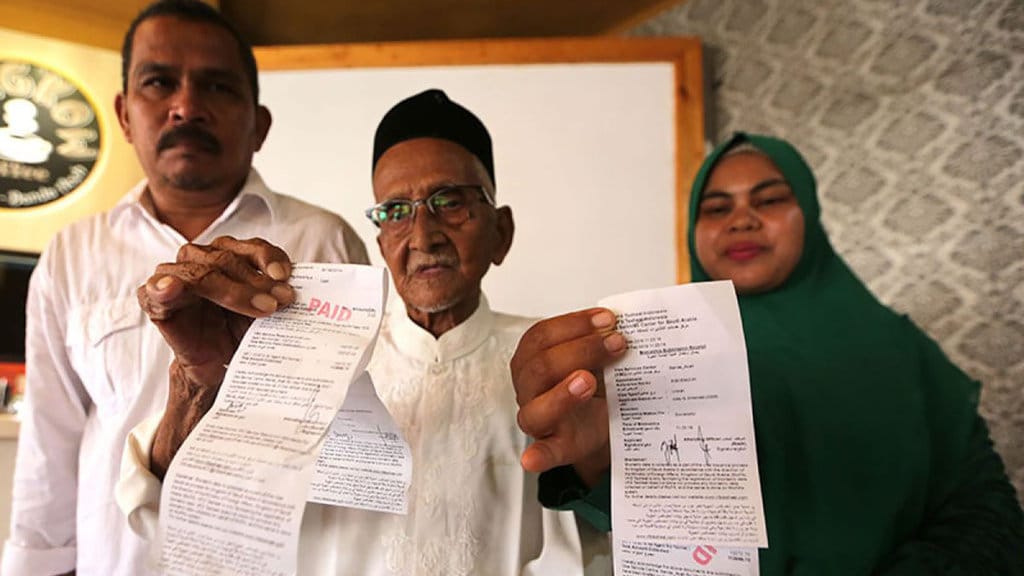Nyak Sandang (tengah) didampingi anaknya Khaidar (kiri) dan menantu memperlihatkan tiket umrah dari bantuan Presiden Joko Widodo di Banda Aceh, Senin (18/2/2019). (Antara Aceh/Irwansyah Putra) Nyak Sandang