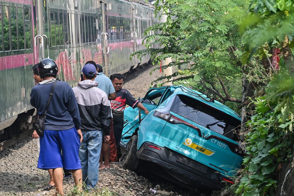 Kereta api (KA) jarak jauh melintas di samping taksi listrik Green SM yang rusak pascakecelakaan KRL Commuter Line dan KA Argo Bromo Anggrek di Stasiun Bekasi Timur, Bekasi, Jawa Barat, Selasa (28/4/2026). Komite Nasional Keselamatan Transportasi (KNKT) mengerahkan tim investigasi untuk mengumpulkan fakta terkait kecelakaan kereta api di Stasiun Bekasi Timur pada Senin (27/4) malam. ANTARA FOTO/Fakhri Hermansyah/nz Pascakecelakaan kereta api di Bekasi Timur