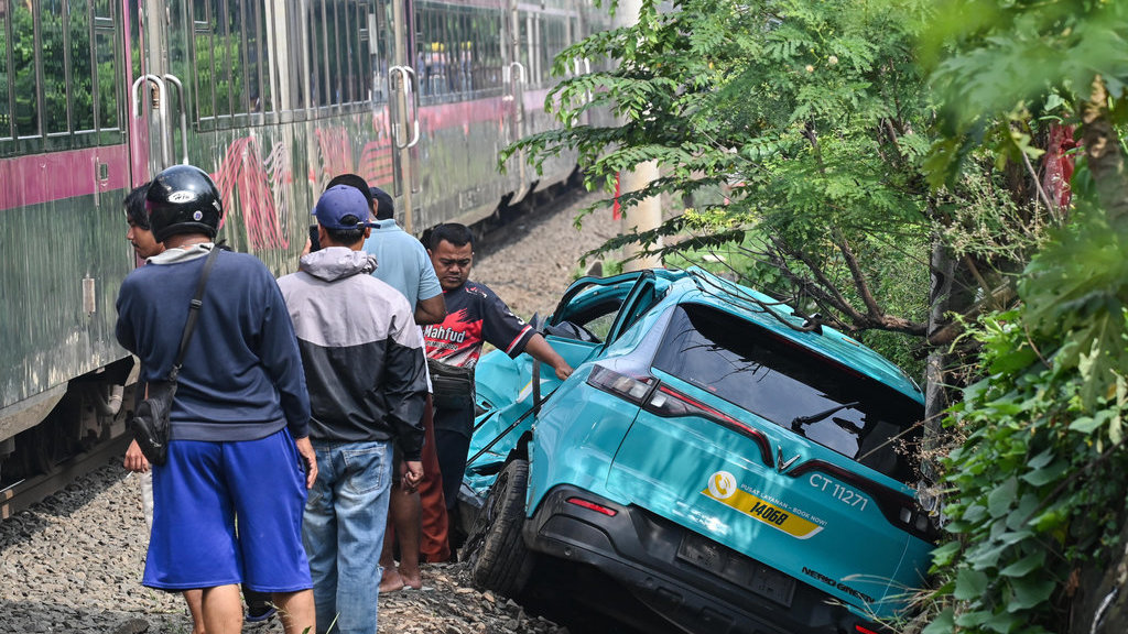 Kereta api (KA) jarak jauh melintas di samping taksi listrik Green SM yang rusak pascakecelakaan KRL Commuter Line dan KA Argo Bromo Anggrek di Stasiun Bekasi Timur, Bekasi, Jawa Barat, Selasa (28/4/2026). Komite Nasional Keselamatan Transportasi (KNKT) mengerahkan tim investigasi untuk mengumpulkan fakta terkait kecelakaan kereta api di Stasiun Bekasi Timur pada Senin (27/4) malam. ANTARA FOTO/Fakhri Hermansyah/nz Pascakecelakaan kereta api di Bekasi Timur